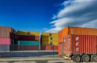 a truck is parked in front of a bunch of shipping containers by Bernd 📷 Dittrich courtesy of Unsplash.