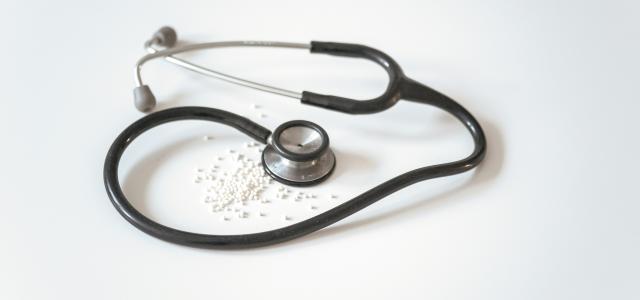 black and silver stethoscope on white surface by Markus Frieauff courtesy of Unsplash.